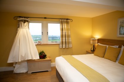 Wedding dress on hanger in front of window in a bedroom